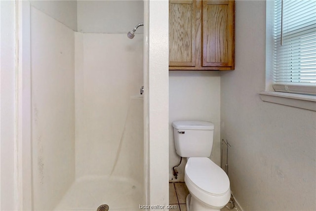 bathroom featuring tile patterned flooring, toilet, and walk in shower