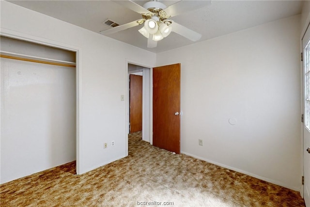 unfurnished bedroom featuring multiple windows, a closet, light colored carpet, and ceiling fan