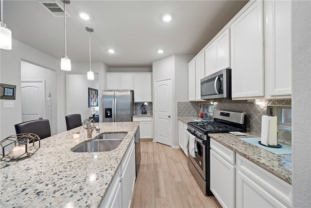 24107 Noble Darcy Ln, Katy, TX 77493 - kitchen featuring appliances with stainless steel finishes, a sink, light wood-style flooring, tasteful backsplash, and white cabinetry
