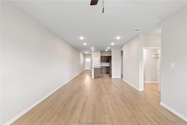 unfurnished living room featuring ceiling fan, light hardwood / wood-style floors, and sink