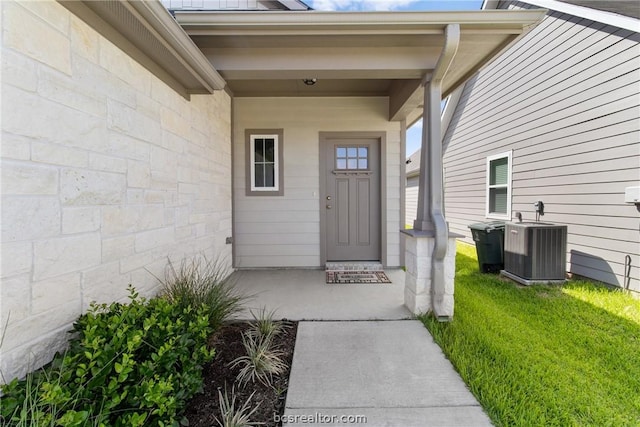 property entrance with a lawn and cooling unit