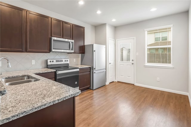 996 Marquis Dr, Bryan, TX 77803 - kitchen featuring appliances with stainless steel finishes, a sink, light wood-style flooring, dark brown cabinetry, and recessed lighting