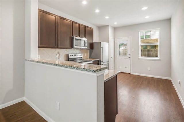 996 Marquis Dr, Bryan, TX 77803 - kitchen featuring appliances with stainless steel finishes, dark wood-style floors, decorative backsplash, light stone counters, and recessed lighting