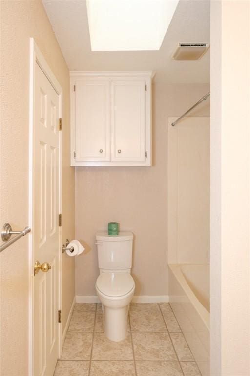 bathroom with tile patterned floors, toilet, and a skylight