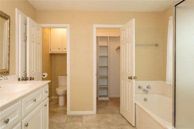 bathroom featuring a washtub, vanity, tile patterned flooring, and toilet