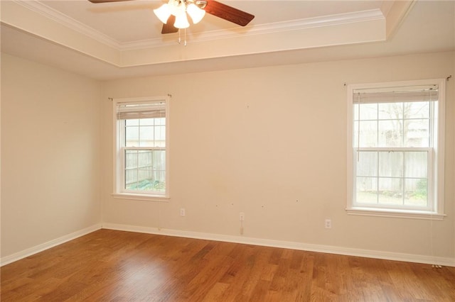 unfurnished room featuring a raised ceiling, wood-type flooring, a healthy amount of sunlight, and ceiling fan