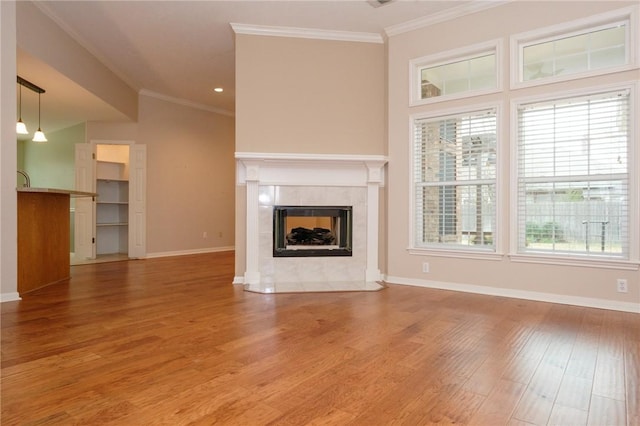 unfurnished living room featuring hardwood / wood-style flooring, ornamental molding, and a tile fireplace