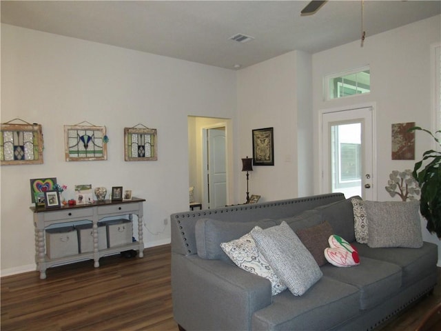 living area featuring visible vents, baseboards, ceiling fan, and dark wood-style floors