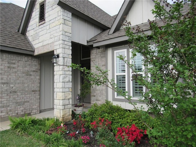 view of property exterior featuring board and batten siding, a shingled roof, and stone siding