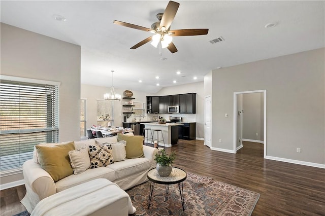 living room with vaulted ceiling, dark hardwood / wood-style floors, and ceiling fan with notable chandelier