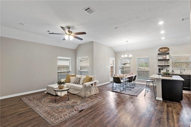 living room with vaulted ceiling, dark hardwood / wood-style flooring, and ceiling fan with notable chandelier