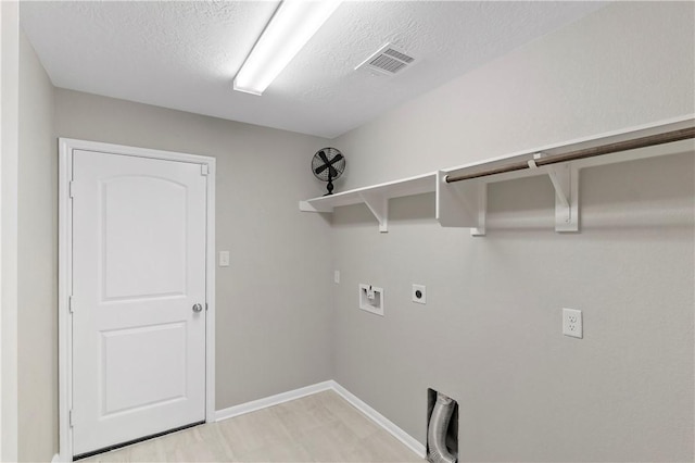 washroom featuring washer hookup, light hardwood / wood-style floors, hookup for an electric dryer, and a textured ceiling