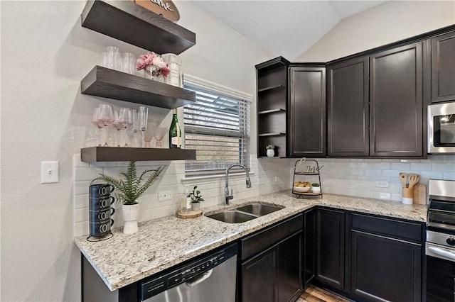 kitchen with light stone countertops, sink, backsplash, vaulted ceiling, and appliances with stainless steel finishes