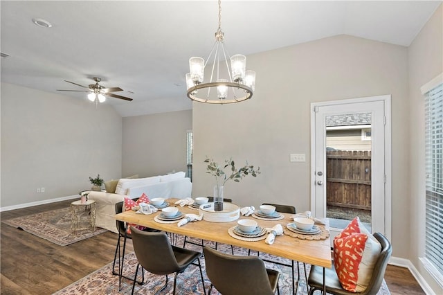 dining room featuring ceiling fan with notable chandelier, vaulted ceiling, and wood-type flooring