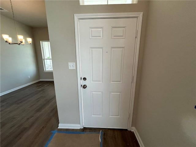 entryway with dark wood-type flooring, an inviting chandelier, and a healthy amount of sunlight