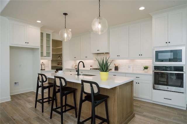 kitchen with built in microwave, wood finished floors, stainless steel oven, and a sink
