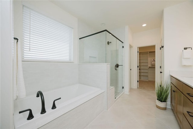 bathroom with a shower stall, a bath, tile patterned floors, vanity, and a walk in closet