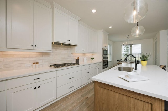 kitchen featuring stainless steel appliances, white cabinets, backsplash, light wood finished floors, and a sink
