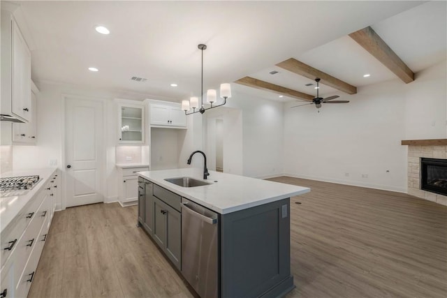 kitchen featuring sink, white cabinetry, hanging light fixtures, dishwasher, and an island with sink