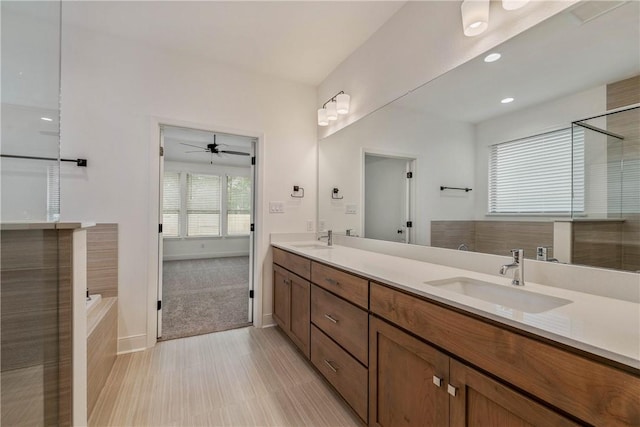 bathroom with ceiling fan, vanity, and a washtub