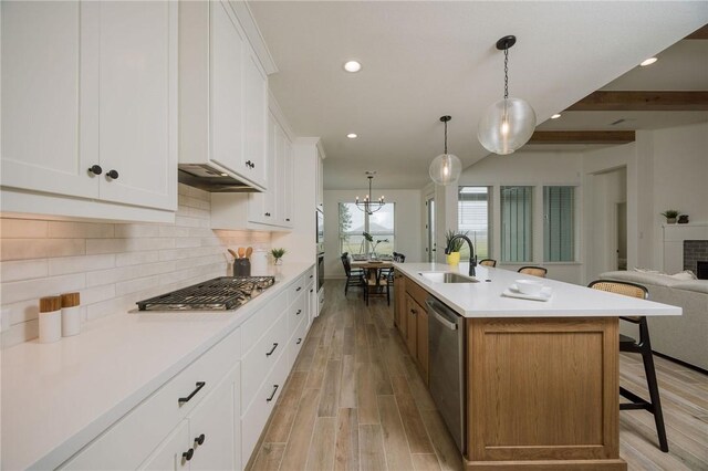 kitchen featuring a sink, stainless steel appliances, a kitchen bar, tasteful backsplash, and open floor plan