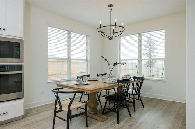 dining space with light wood finished floors, a notable chandelier, and baseboards