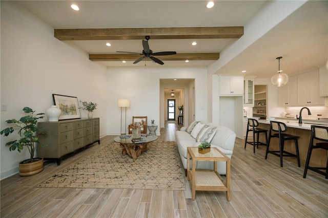 living area featuring beam ceiling, recessed lighting, a ceiling fan, and light wood-style flooring