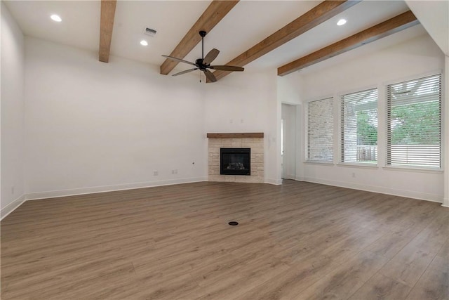 unfurnished living room with beamed ceiling, ceiling fan, dark hardwood / wood-style floors, and a fireplace