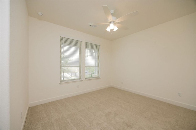 spare room featuring baseboards, light carpet, and ceiling fan