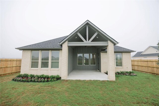 rear view of house featuring brick siding, a fenced backyard, board and batten siding, and a patio area
