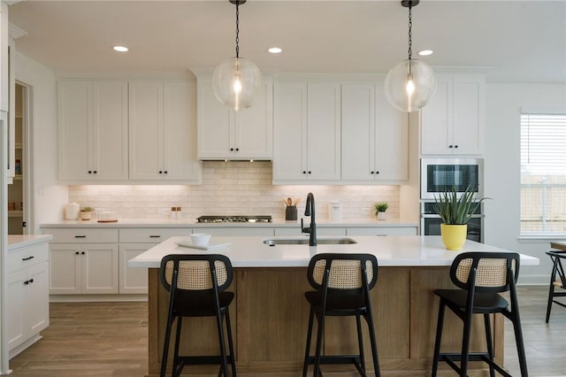 kitchen with white cabinetry, light countertops, light wood finished floors, and a sink