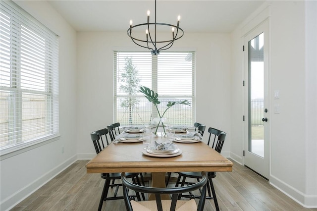 dining room featuring a chandelier, plenty of natural light, light wood finished floors, and baseboards