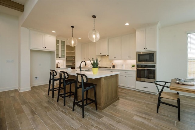 kitchen featuring appliances with stainless steel finishes, white cabinetry, backsplash, and a sink