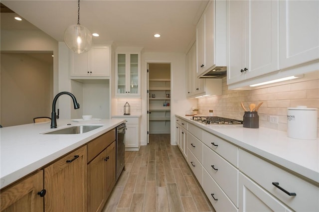 kitchen with a sink, stainless steel appliances, light wood-type flooring, light countertops, and white cabinets