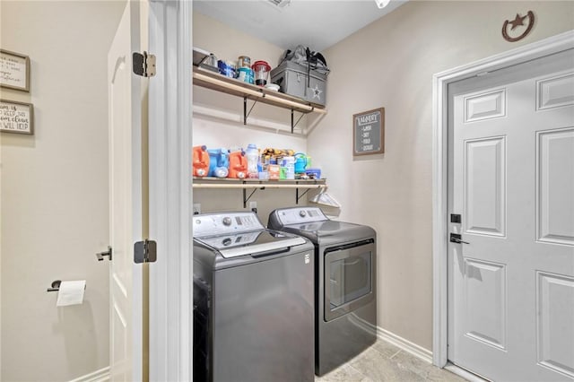 washroom with baseboards, washer and clothes dryer, and laundry area