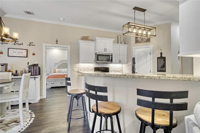 kitchen featuring white cabinetry, dark hardwood / wood-style floors, tasteful backsplash, light stone countertops, and decorative light fixtures