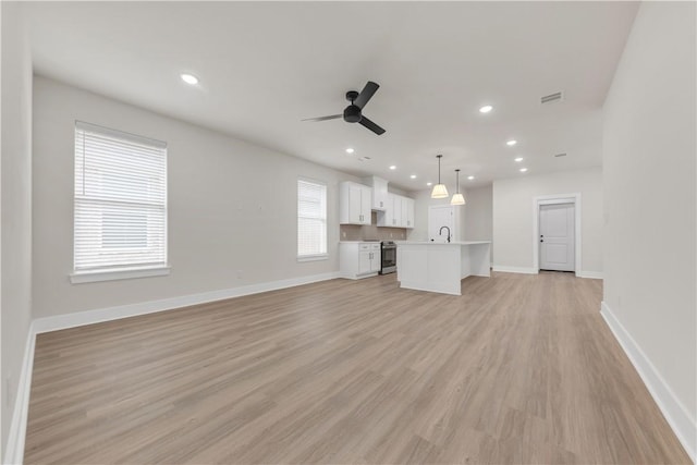 unfurnished living room with ceiling fan, sink, and light hardwood / wood-style flooring