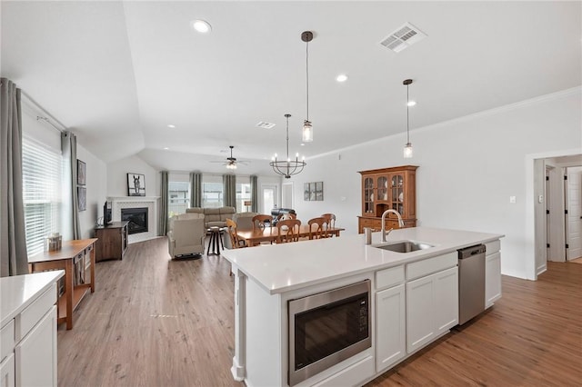 kitchen with appliances with stainless steel finishes, sink, a center island with sink, decorative light fixtures, and white cabinets