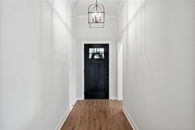 entryway featuring an inviting chandelier, ornamental molding, and hardwood / wood-style flooring