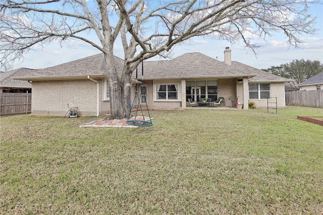 back of house featuring a fenced backyard, brick siding, a yard, a chimney, and a patio area