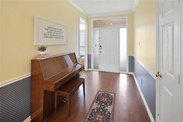 foyer with ornamental molding, a wainscoted wall, and wood finished floors