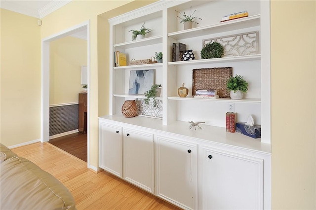 interior space with light wood-style floors, built in features, and ornamental molding