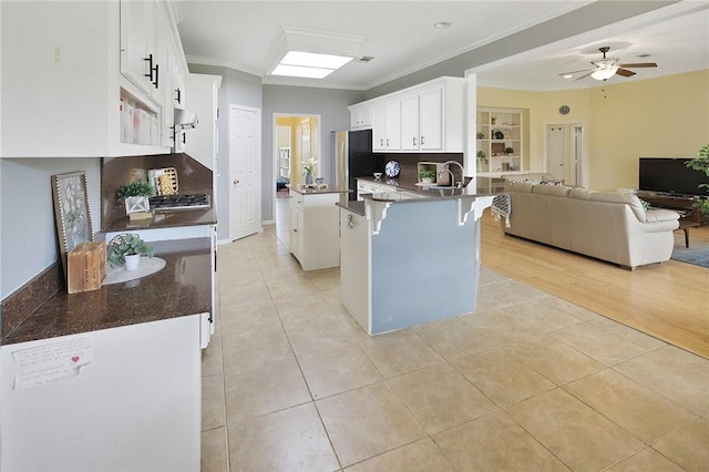 kitchen featuring light tile patterned floors, white cabinets, a breakfast bar area, open floor plan, and a peninsula