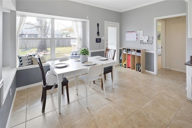 dining space featuring light tile patterned floors, baseboards, and ornamental molding