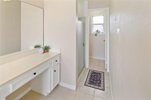 bathroom with tile patterned flooring, a shower stall, vanity, and baseboards