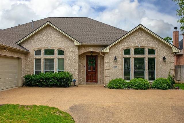 view of front of house featuring driveway, an attached garage, a shingled roof, and brick siding