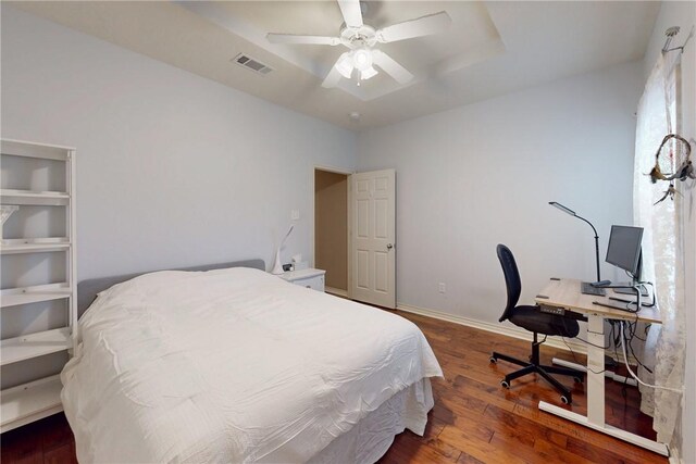 bedroom featuring wood finished floors, a raised ceiling, a desk, baseboards, and a ceiling fan