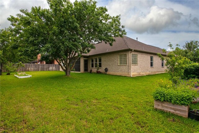 back of house featuring a garden and brick siding