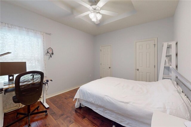 bedroom featuring dark wood-type flooring, a desk, baseboards, and a ceiling fan
