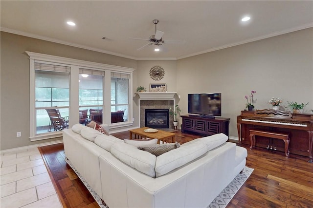 living area with ceiling fan, a glass covered fireplace, crown molding, recessed lighting, and baseboards